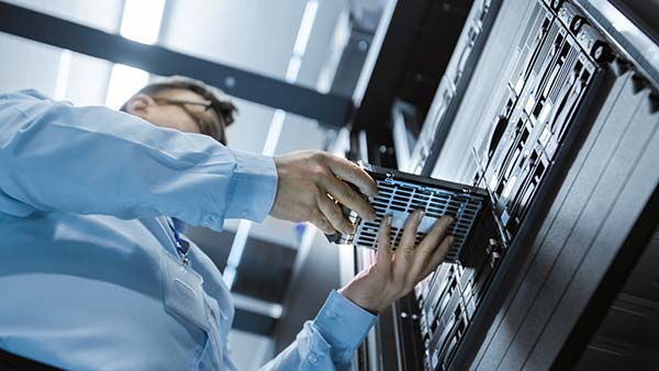 123NET Smart Hands service technician replacing drive in front of a colocated server stack in a data center